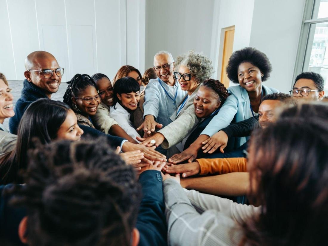 Coaching d'équipe en entreprise : collaborateurs réunis en cercle, les mains rassemblées